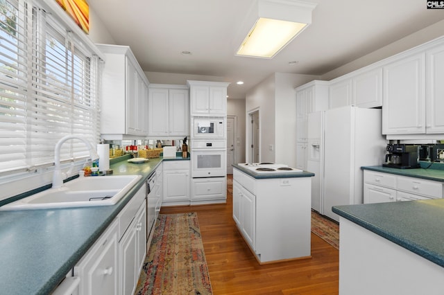 kitchen featuring white cabinetry, white appliances, wood-type flooring, a kitchen island, and sink