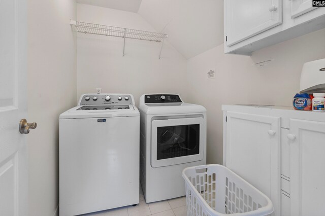 clothes washing area with washing machine and dryer, cabinets, and light tile patterned floors