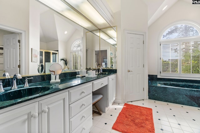 bathroom with tile patterned flooring, a tub to relax in, vanity, and vaulted ceiling