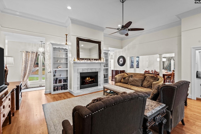 living room with light hardwood / wood-style floors, ceiling fan, ornamental molding, and a tiled fireplace