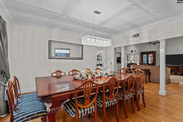 dining area featuring decorative columns, ornamental molding, ceiling fan with notable chandelier, and light wood-type flooring