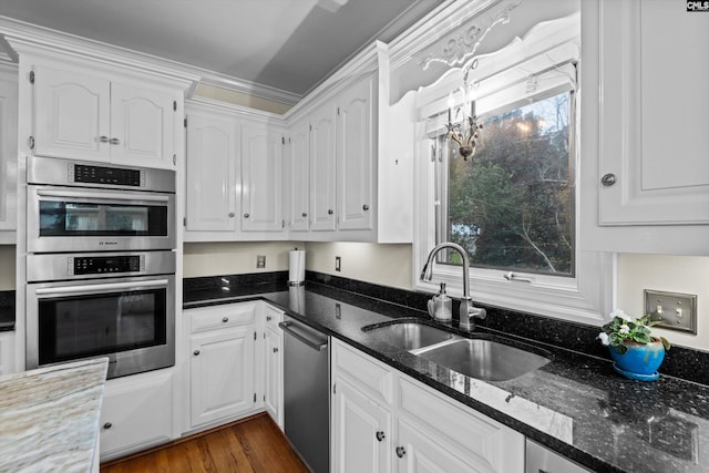 kitchen featuring white cabinetry, sink, stainless steel appliances, dark hardwood / wood-style flooring, and dark stone countertops