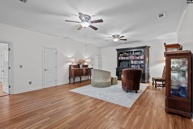 living area with light hardwood / wood-style flooring, ceiling fan, and ornamental molding