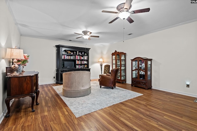 sitting room with ceiling fan, dark wood-type flooring, and ornamental molding