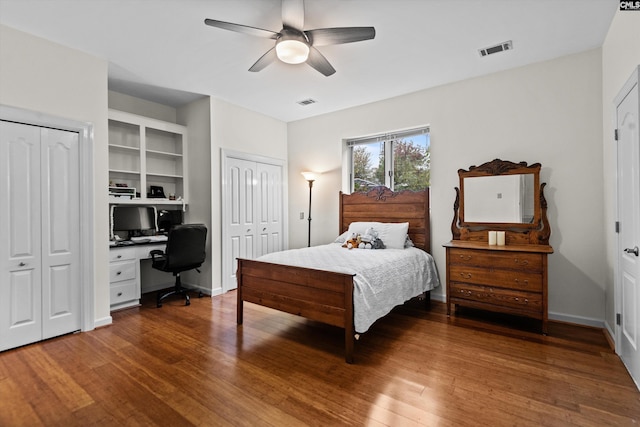 bedroom with ceiling fan, wood-type flooring, and two closets