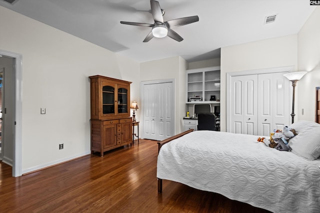 bedroom with two closets, ceiling fan, and dark wood-type flooring