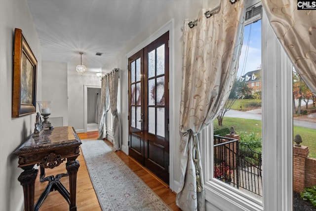 entryway featuring french doors, light hardwood / wood-style floors, and a notable chandelier