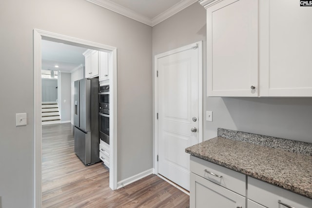 kitchen with stainless steel fridge, white cabinets, light hardwood / wood-style floors, and light stone counters