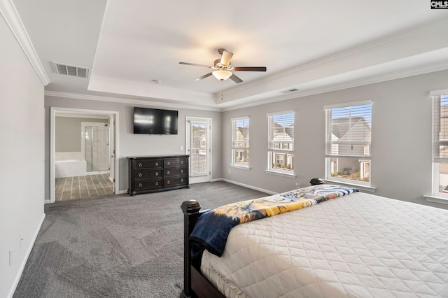 carpeted bedroom featuring a tray ceiling, ensuite bath, ceiling fan, and ornamental molding