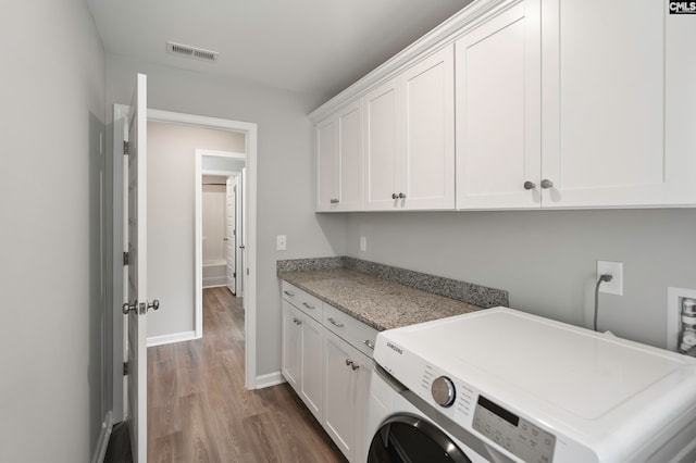 laundry area with hardwood / wood-style floors, cabinets, and washer / clothes dryer