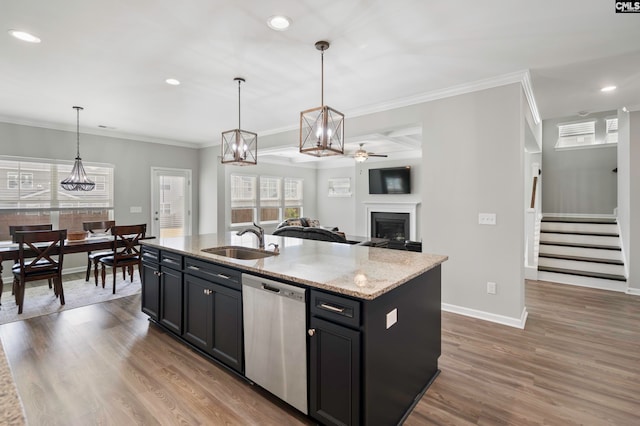 kitchen with stainless steel dishwasher, sink, a kitchen island with sink, and hanging light fixtures