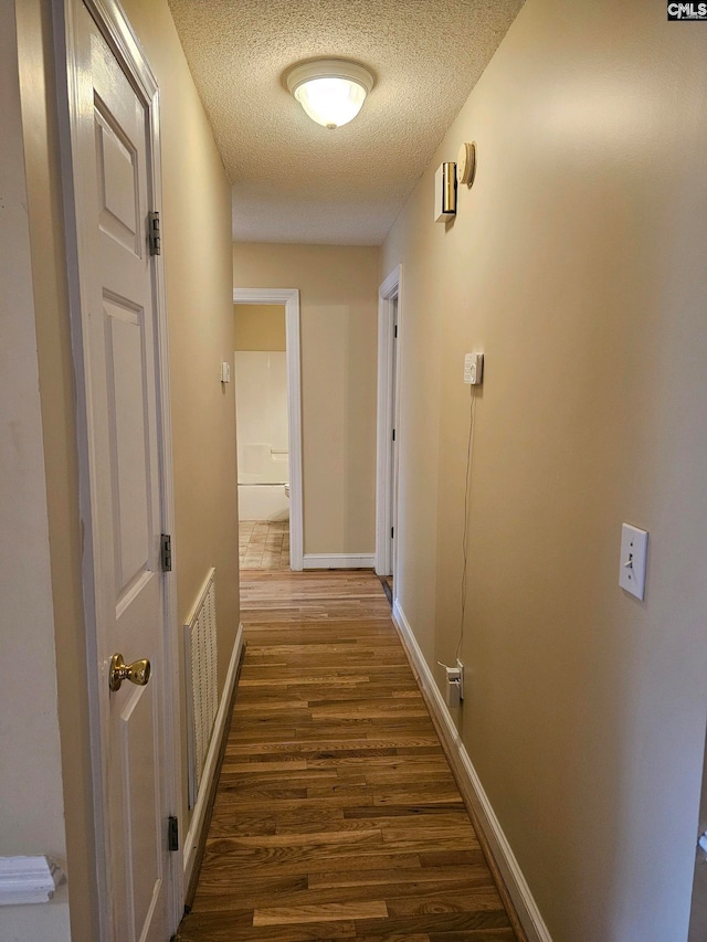 hall featuring a textured ceiling and dark hardwood / wood-style flooring