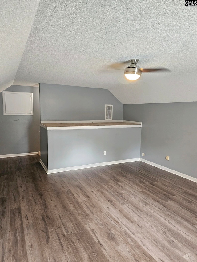 bonus room featuring vaulted ceiling, dark hardwood / wood-style flooring, and a textured ceiling