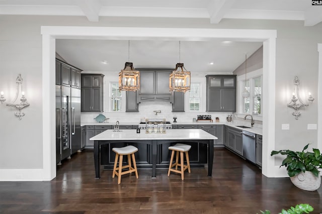 kitchen featuring backsplash, decorative light fixtures, and an island with sink