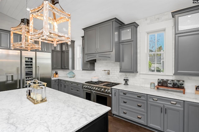 kitchen with tasteful backsplash, gray cabinets, hanging light fixtures, and high end appliances