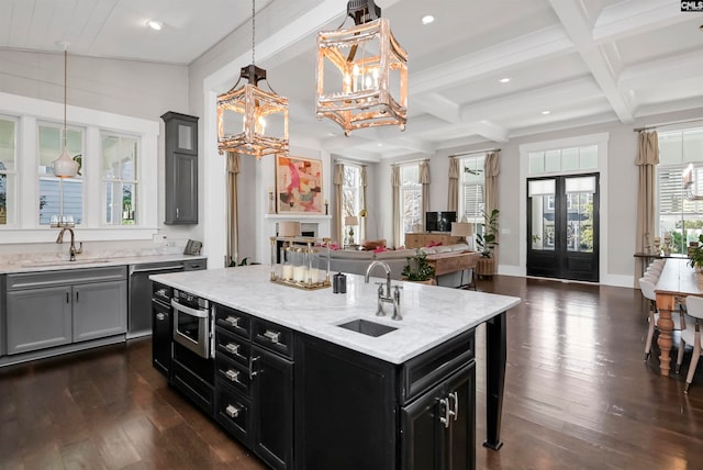 kitchen with dark wood-type flooring, an island with sink, and hanging light fixtures