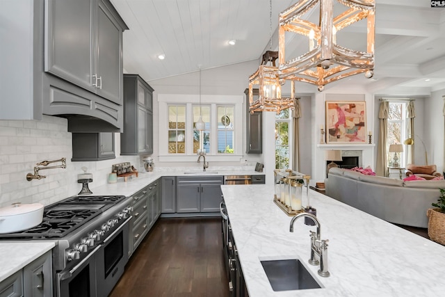 kitchen featuring double oven range, gray cabinets, light stone countertops, and a healthy amount of sunlight