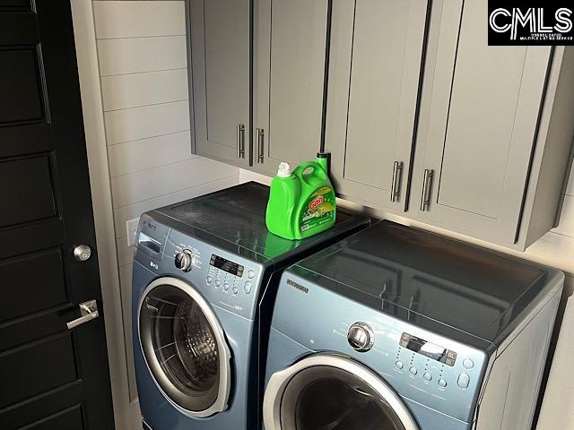 clothes washing area featuring cabinets and washing machine and clothes dryer