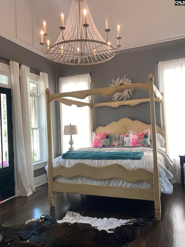 bedroom with dark hardwood / wood-style flooring, an inviting chandelier, and multiple windows