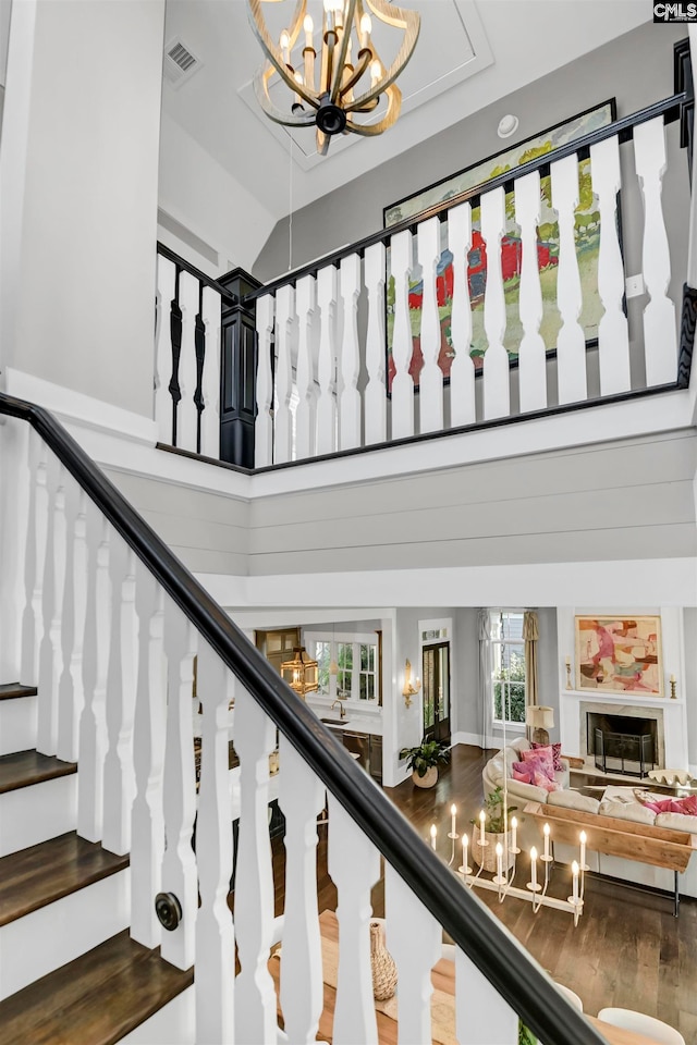 stairs featuring a chandelier, hardwood / wood-style floors, and high vaulted ceiling