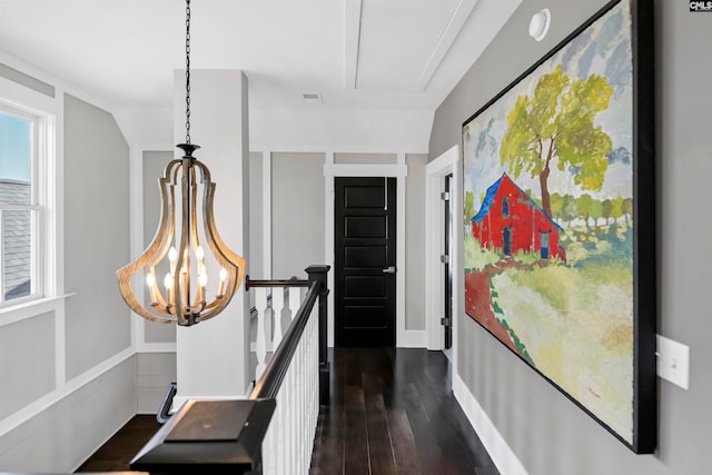 hallway with dark hardwood / wood-style flooring, lofted ceiling, and an inviting chandelier