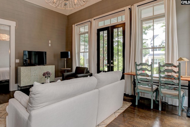 living room featuring french doors, dark wood-type flooring, and an inviting chandelier