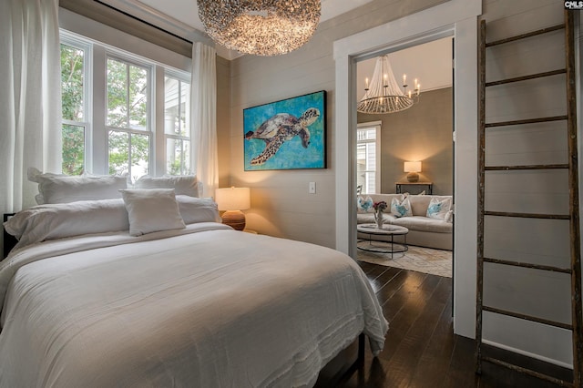 bedroom with a chandelier, wooden walls, and dark wood-type flooring