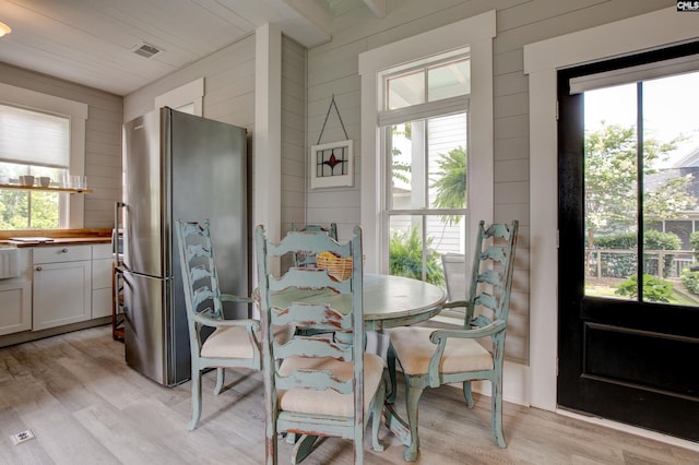 dining area featuring light wood-type flooring and wooden walls