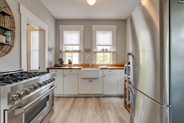 kitchen with butcher block countertops, white cabinetry, light hardwood / wood-style flooring, and stainless steel appliances