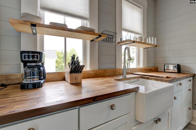 kitchen featuring a wealth of natural light, white cabinets, and wooden counters