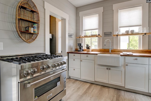 kitchen with a wealth of natural light, sink, high end range, and wooden counters