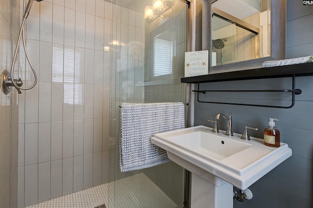 bathroom featuring sink, an enclosed shower, and tile walls