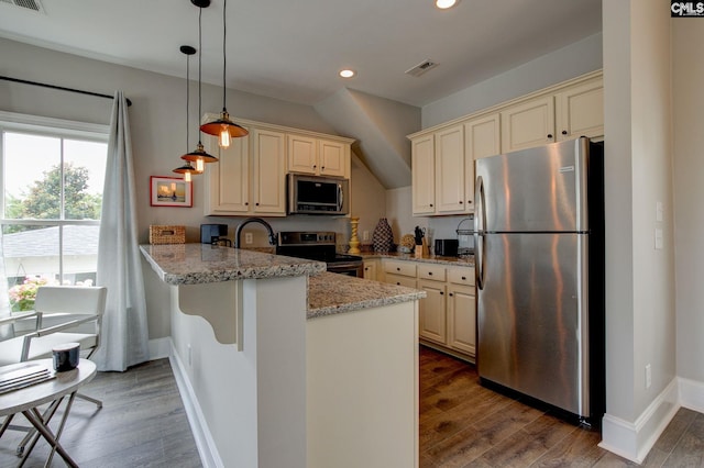 kitchen featuring kitchen peninsula, cream cabinetry, stainless steel appliances, and hardwood / wood-style flooring