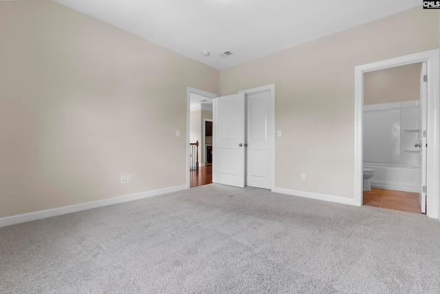 unfurnished bedroom with ensuite bath and light colored carpet