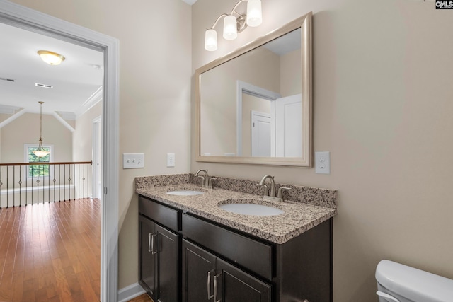 bathroom with hardwood / wood-style floors, vanity, toilet, and vaulted ceiling