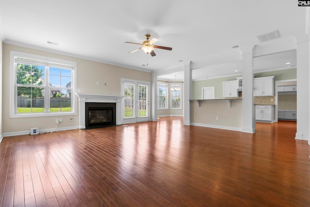 unfurnished living room featuring ceiling fan with notable chandelier, dark hardwood / wood-style floors, and crown molding