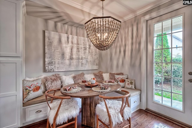 dining room with hardwood / wood-style flooring, breakfast area, ornamental molding, and an inviting chandelier