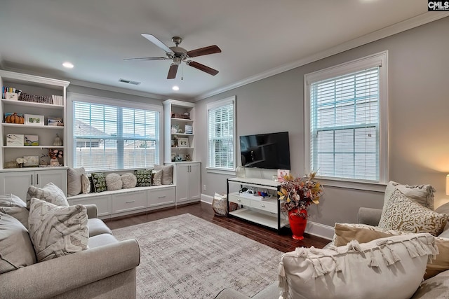 living room with a healthy amount of sunlight, ornamental molding, and dark wood-type flooring