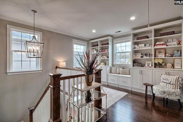 living area featuring dark hardwood / wood-style floors, ornamental molding, and a notable chandelier