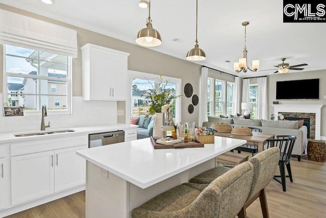 kitchen featuring white cabinets, ceiling fan with notable chandelier, a kitchen island, and sink