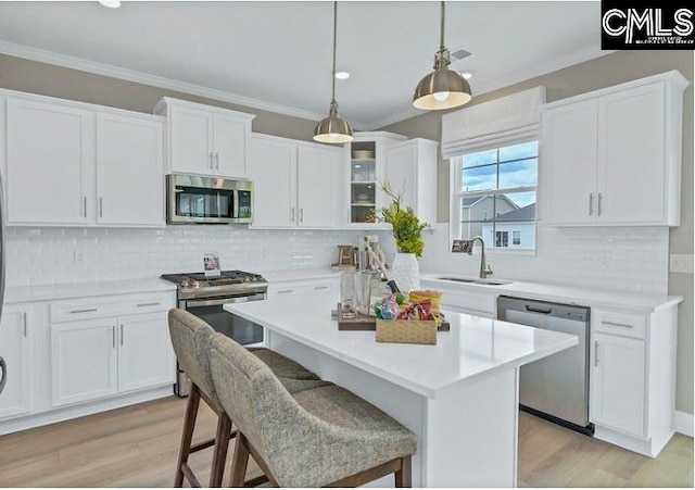 kitchen featuring light wood-type flooring, stainless steel appliances, white cabinetry, and a breakfast bar area