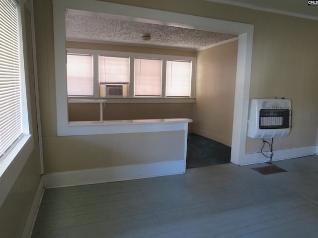 spare room featuring a textured ceiling, heating unit, hardwood / wood-style flooring, and ornamental molding