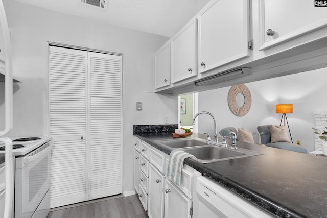 kitchen featuring white appliances, sink, hardwood / wood-style flooring, a textured ceiling, and white cabinetry