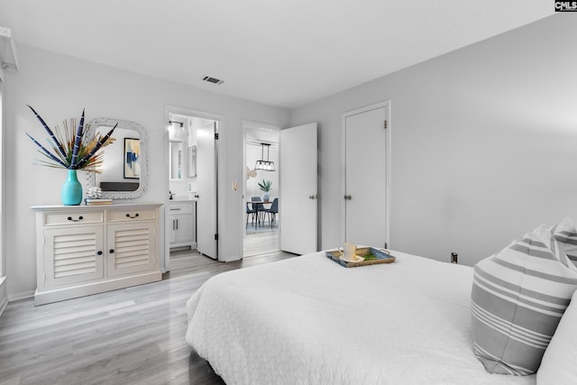 bedroom with ensuite bathroom and light hardwood / wood-style floors