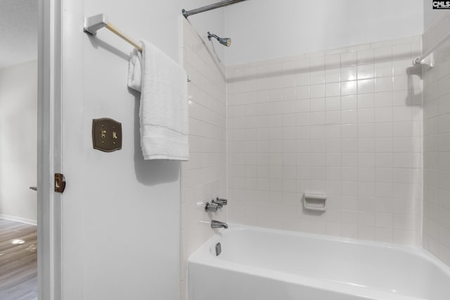 bathroom featuring wood-type flooring and tiled shower / bath