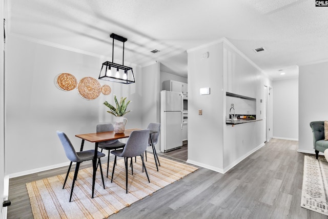 dining area featuring crown molding, a textured ceiling, and light wood-type flooring