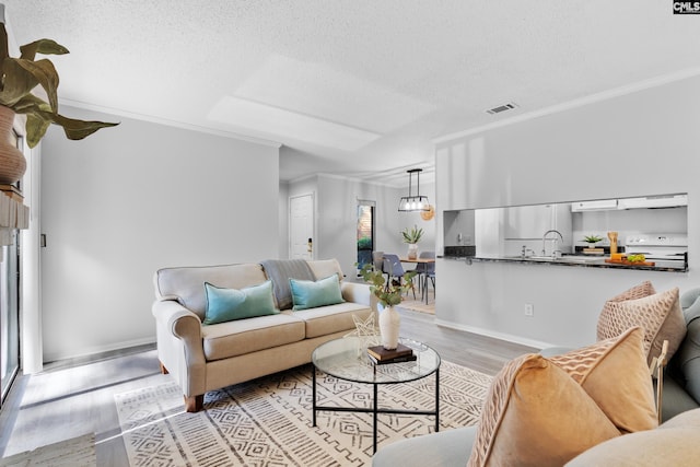 living room with crown molding, plenty of natural light, and light hardwood / wood-style flooring