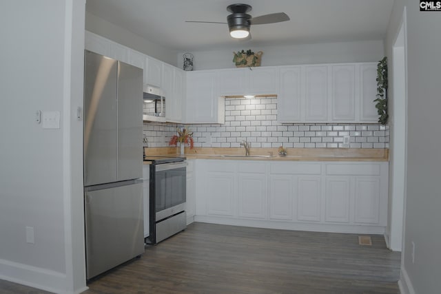 kitchen featuring white cabinets, sink, stainless steel appliances, and dark wood-type flooring