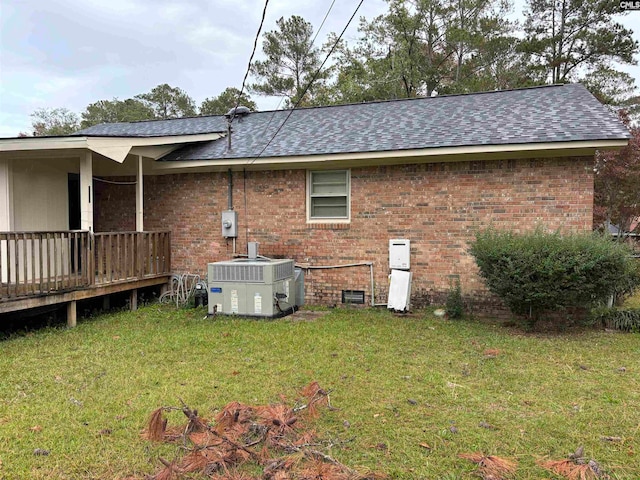 rear view of property featuring a deck, central AC unit, and a lawn