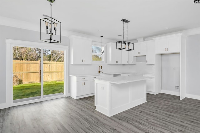 kitchen with sink, dark hardwood / wood-style floors, white cabinets, a kitchen island, and decorative light fixtures